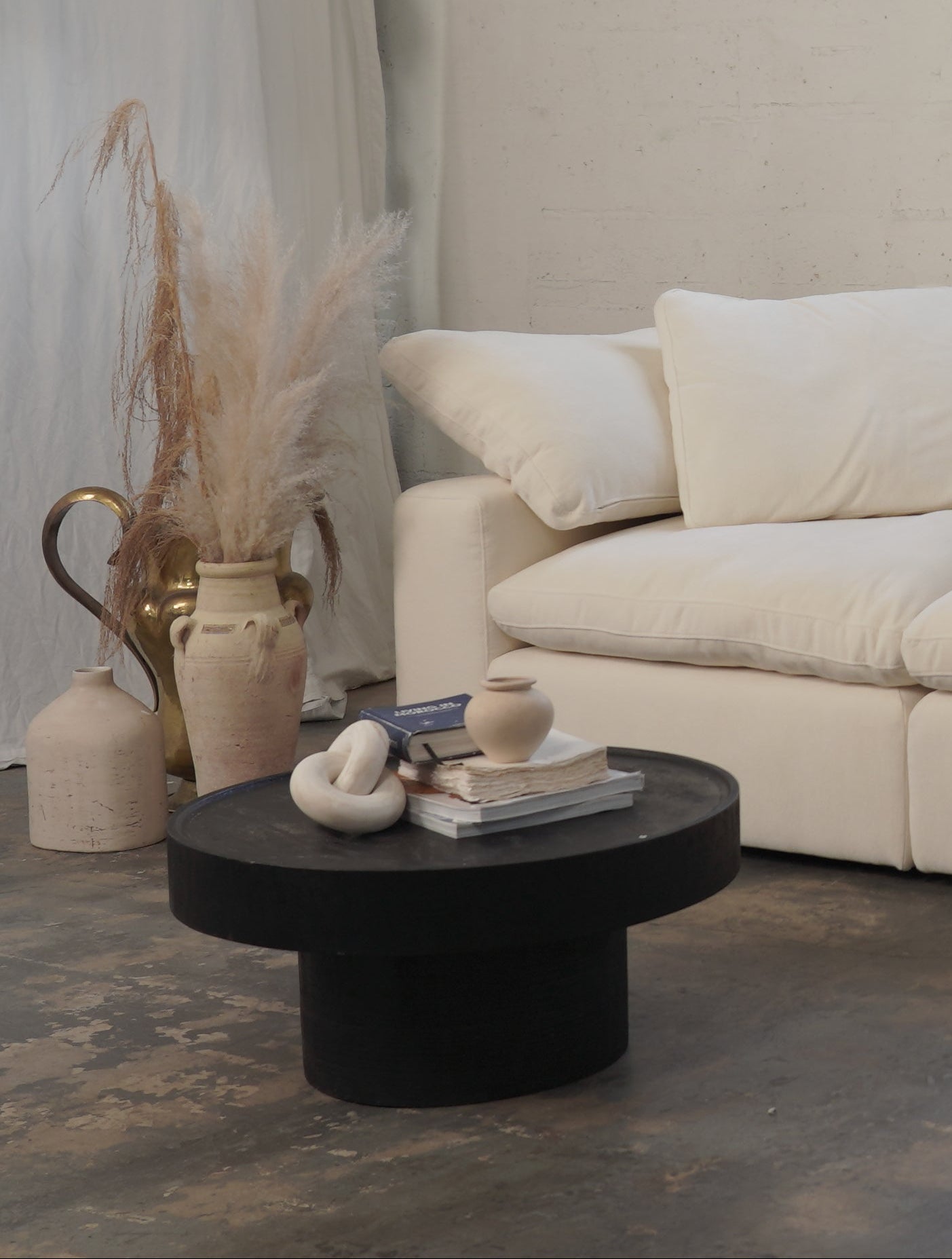 Beige sectional sofa in a room with a brick wall and minimal decor.